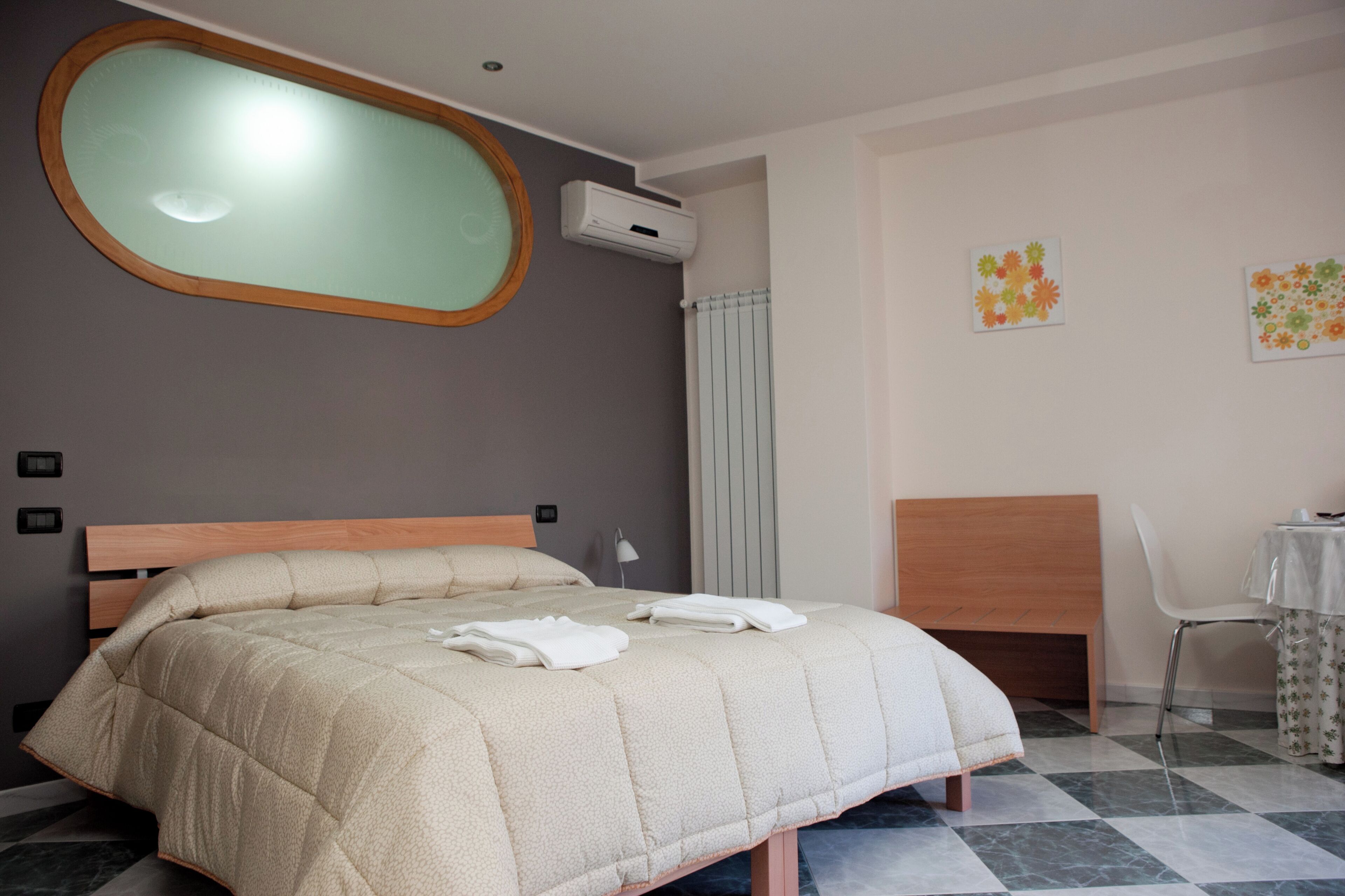Un dormitorio con una cama, una silla, una mesa y un ventanal.