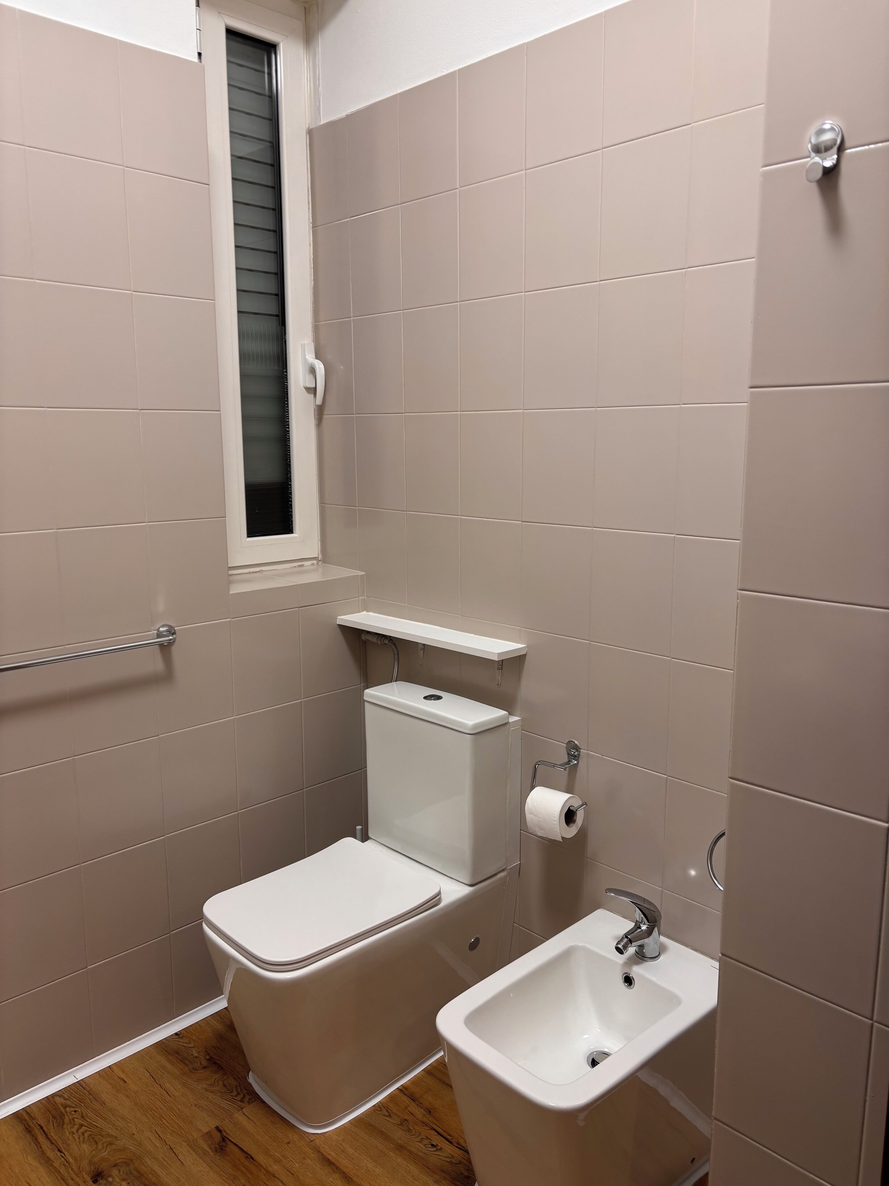 Een kleine badkamer met toilet, hygiëneschuimer en wastafel.