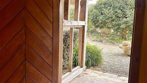 An arched wooden door leading to a stone-tiled patio with a garden view. - Streamside Country Manor - Peaceful Spacious Country Retreat Near Hobbiton (Richmond Downs)