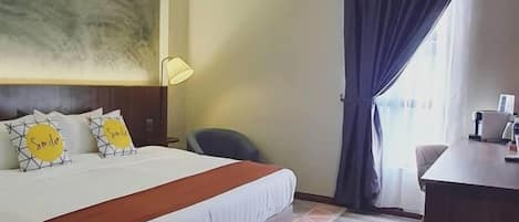 Una habitación de hotel con una cama, un escritorio, una silla, una lámpara y una ventana con cortinas.