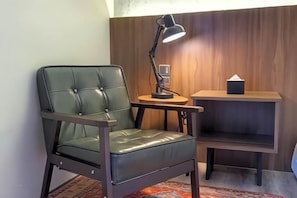 A room with a leather chair, a desk with a lamp, and a small wooden shelf. - Vista Hotel (Tawau)