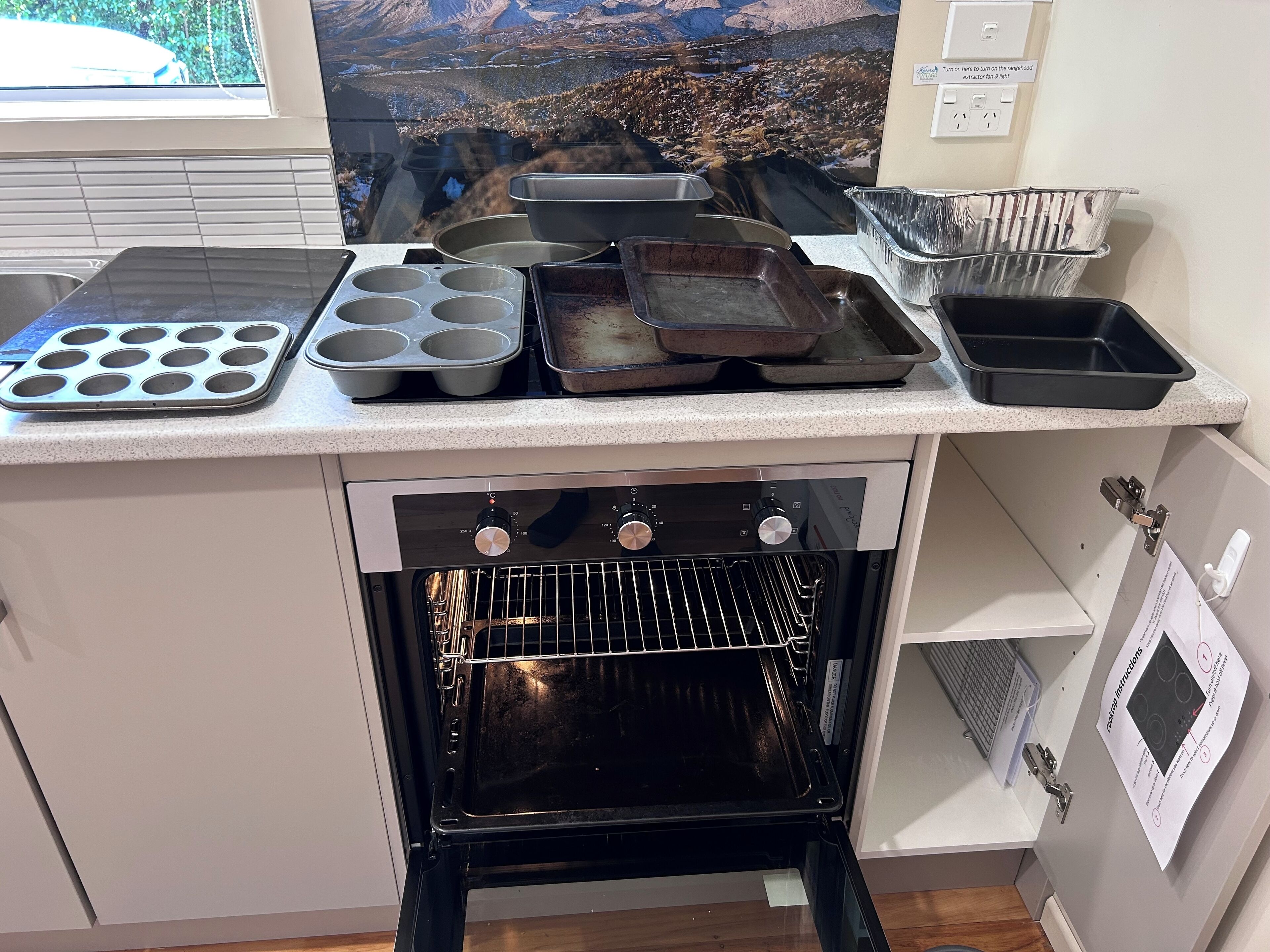 A kitchen with an oven, muffin tray, and baking pans on the counter.