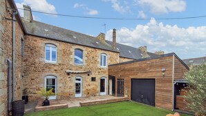 A stone house with a wooden extension, a garage, and a well-maintained lawn. - 4 bedroom nice home in Penvénan (Penvénan)