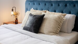 A bed with a tufted headboard, a bedside table with a lamp, and two pillows. - Stylish Plateau Getaway | Steps from Mont-Royal (Montréal)