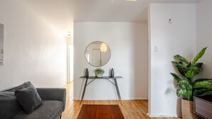 A modern living room with a grey sofa, a wooden coffee table, a round mirror, and a potted plant. - Modern 2BR in Plateau – Steps to Downtown (Montréal)