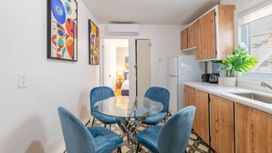 Een moderne keuken met houten kastjes, een glazen eettafel en blauwe stoelen.