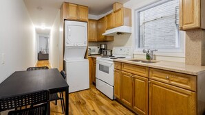 A compact kitchen with wooden cabinets, a white refrigerator, a stove, and a microwave. - Spacious & Trendy 2BR – Heart of Montreal (Montréal)