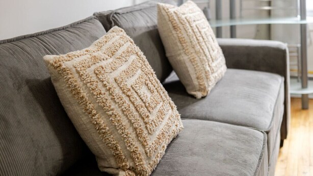 A grey sofa with two beige textured pillows. - Spacious & Trendy 2BR – Heart of Montreal (Montréal)