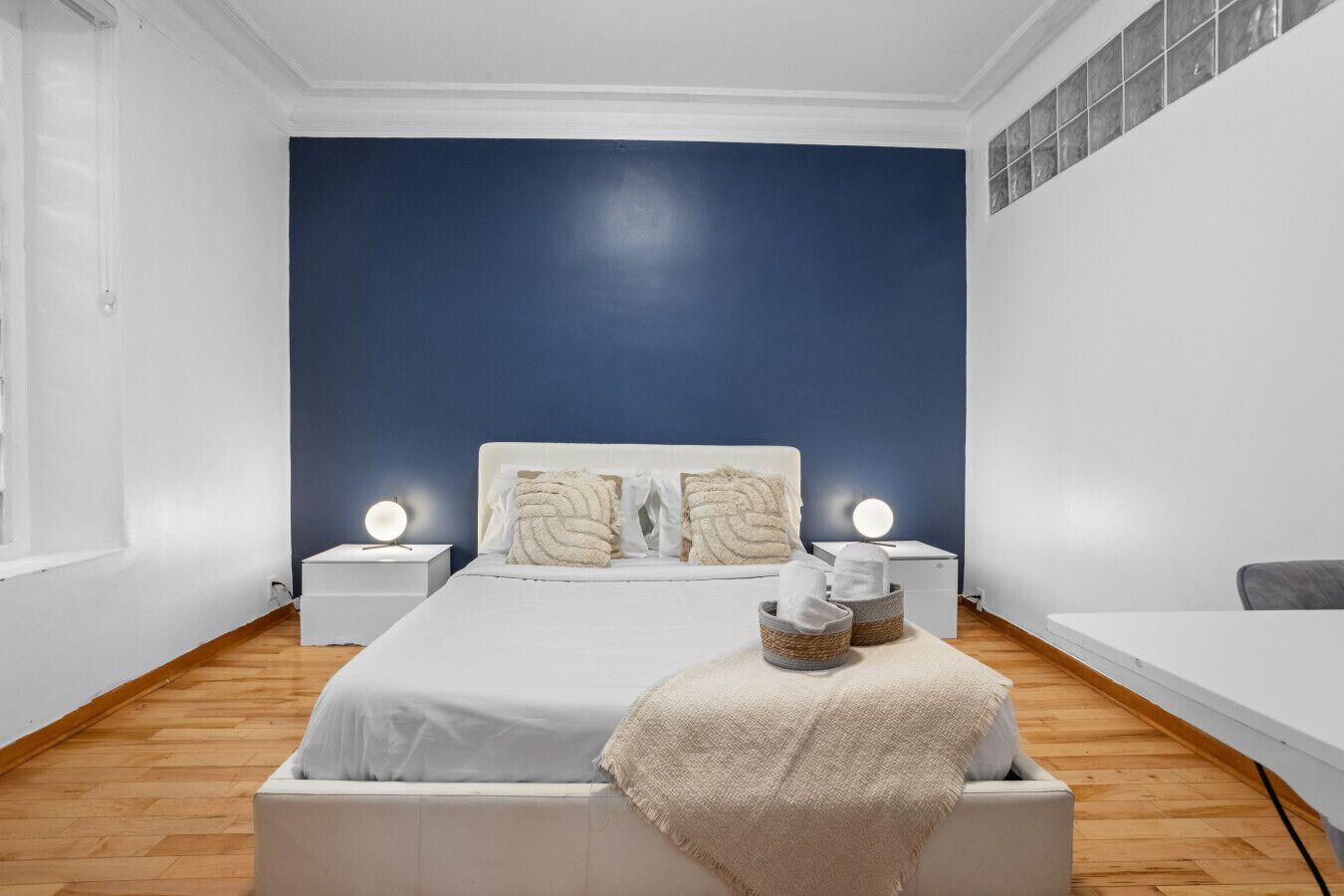Une chambre à coucher avec un lit, des tables de chevet, une lampe, une chaise et une fenêtre.