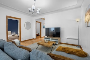 Een moderne woonkamer met een bank, televisie, salontafel en een spiegel.