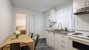 A modern kitchen with white cabinets, a wooden dining table, and a built-in stove.