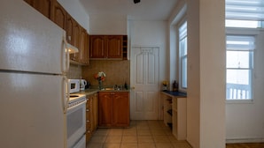 Eine Küche mit Holzschränken, einem weißen Kühlschrank, einer Mikrowelle und einem Spülbecken.