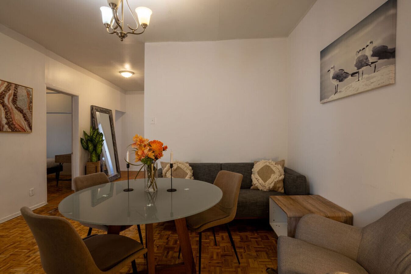 Ein modernes Wohnzimmer mit einem runden Glastisch, zwei Sofas und einem Essbereich.