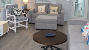 A living room with a grey sofa, a zebra-patterned chair, a round coffee table, and a ceiling fan.