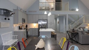 A spacious kitchen with a dining area, a staircase leading to an upper level, and a view of the outside.