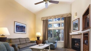 A cozy living room with a sofa, armchairs, a coffee table, a fireplace, and a large window with curtains. - Charming 2-bedroom condo close to ski resort with WiFi in beautiful Zephyr Cove (Zephyr Cove)
