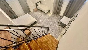 Un dormitorio pequeño y moderno con cama, escritorio y una escalera.