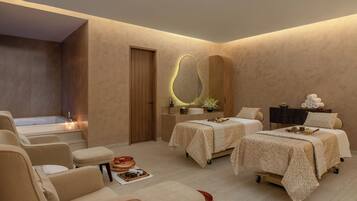 Relax in a serene space with a bathtub, two massage beds, and a cozy seating area.