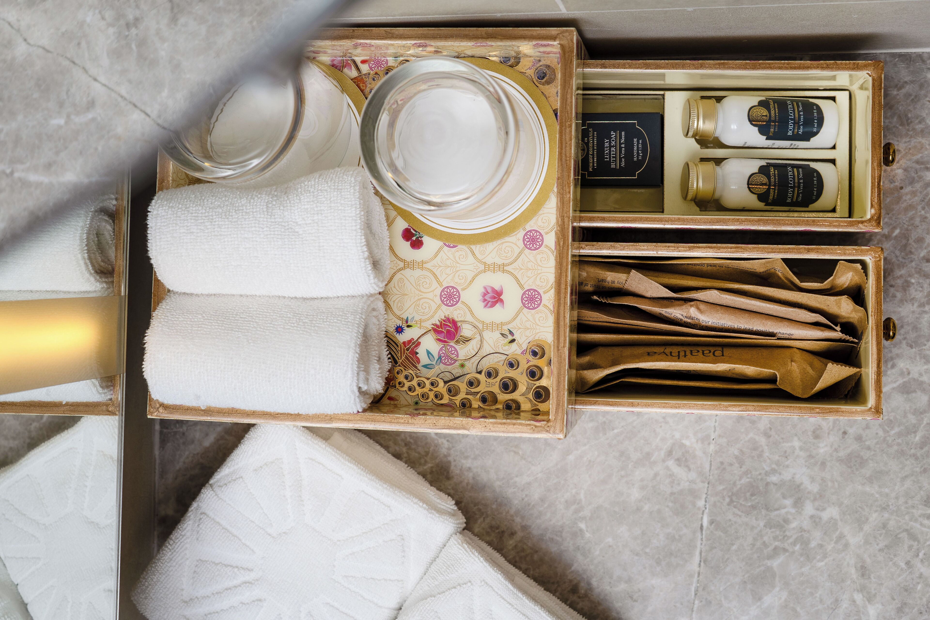 A bathroom with a towel rack, a glass jar, a bottle, and a box of toiletries.