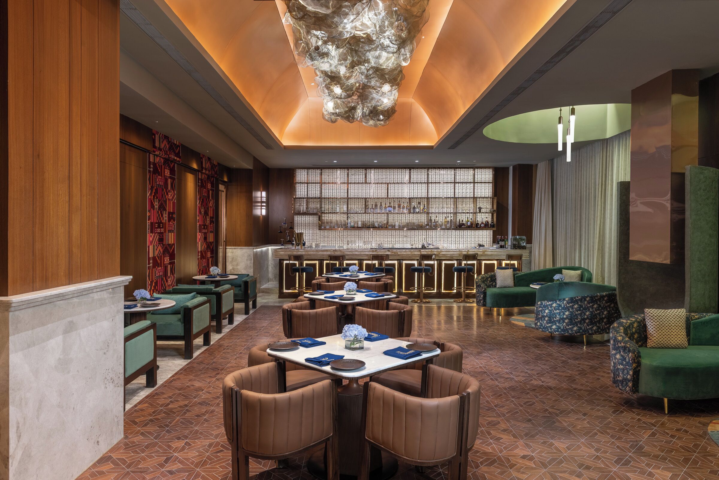 A modern hotel lobby with a bar area, seating arrangements, and a decorative ceiling.