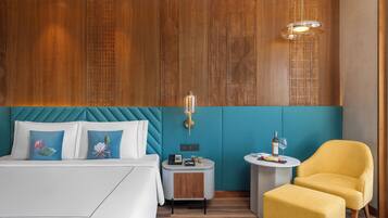 Habitación de hotel con cama, una mesita auxiliar pequeña, una silla y una pared con paneles de madera.