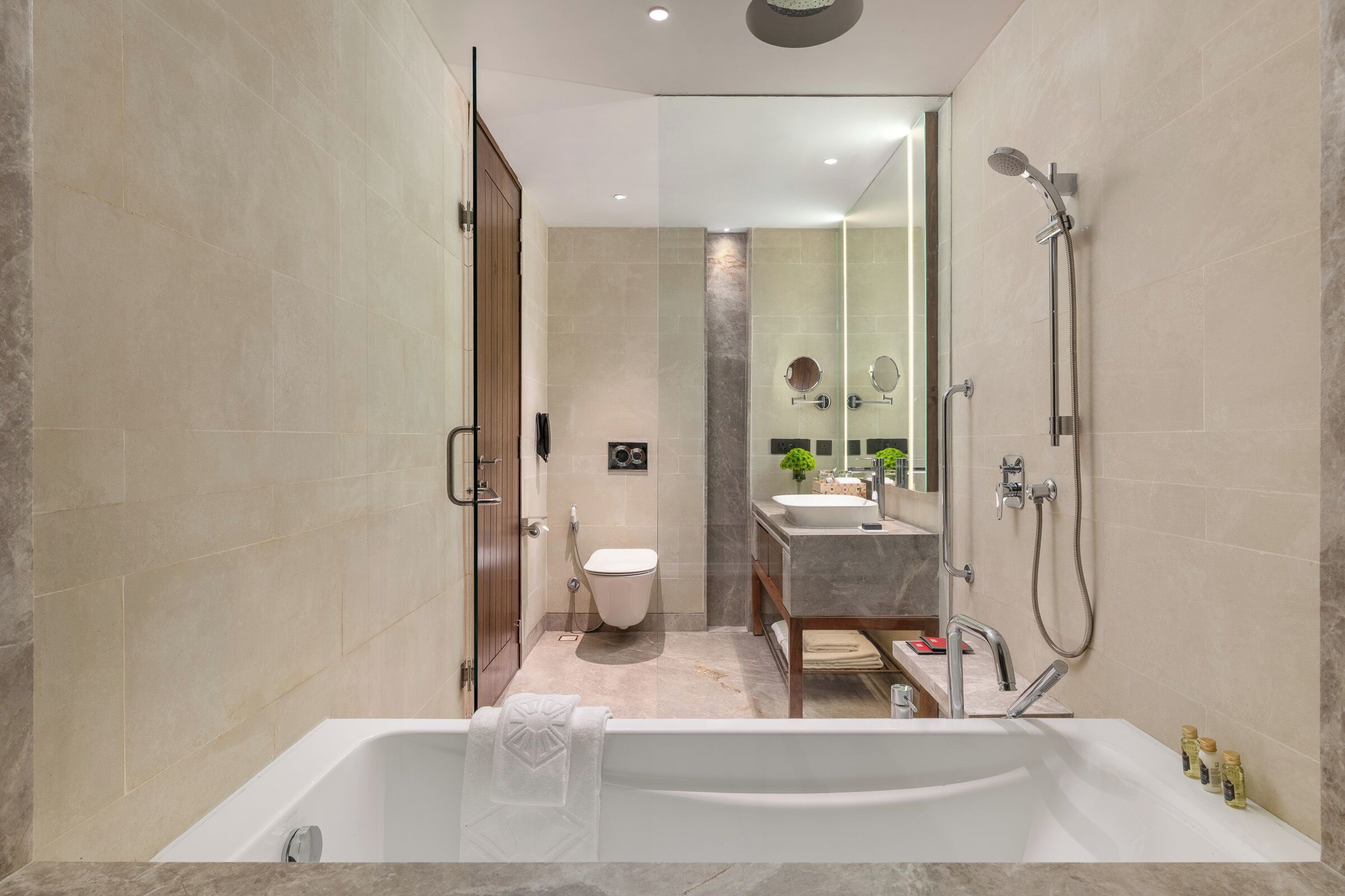 Een moderne badkamer met bad, douche, toilet en wastafel.