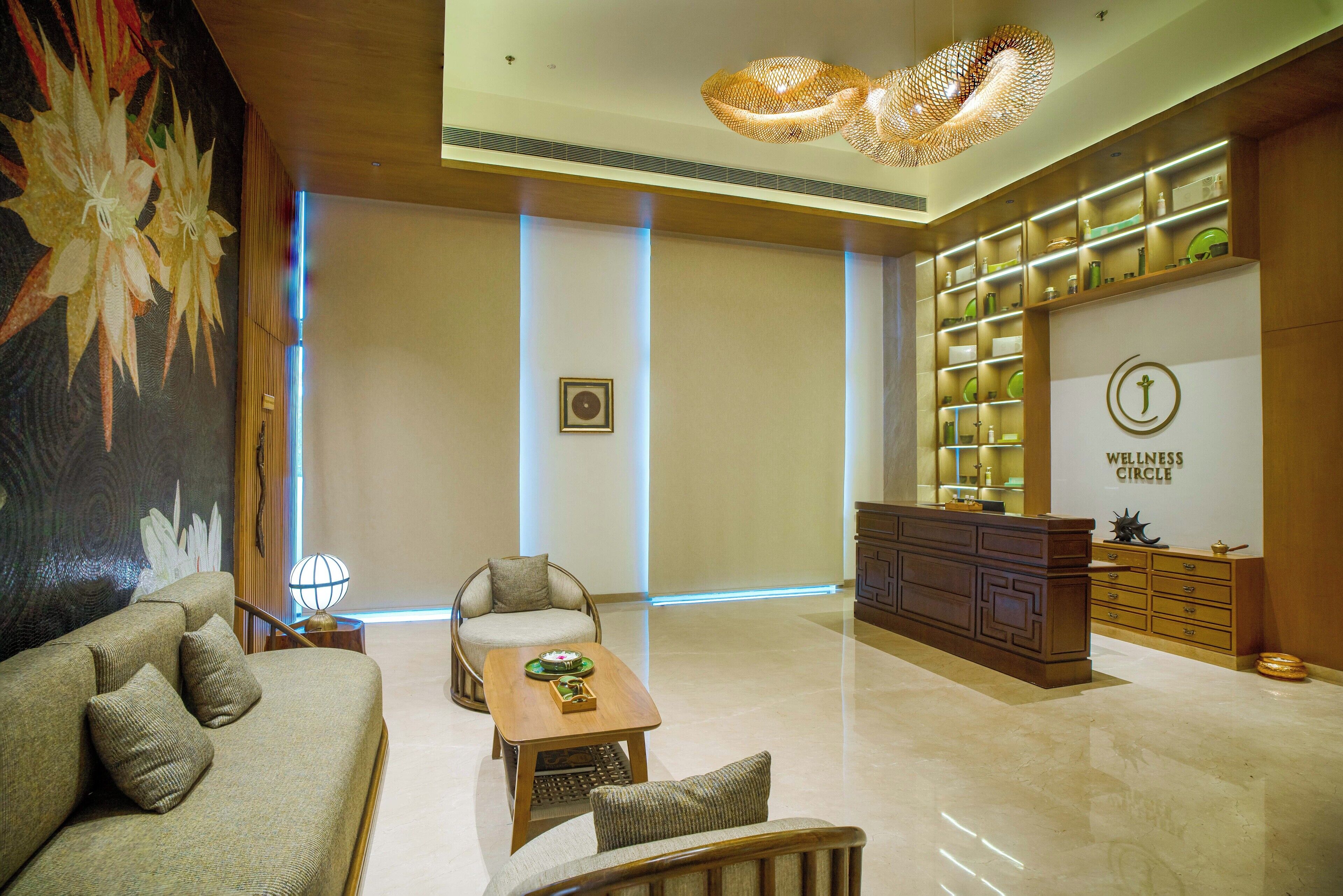 A modern lobby with a sofa, armchairs, a coffee table, a reception desk, and a wellness center sign.