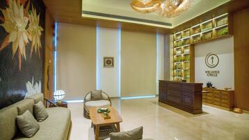 A modern lobby with a sofa, armchairs, a coffee table, a reception desk, and a wellness center sign.