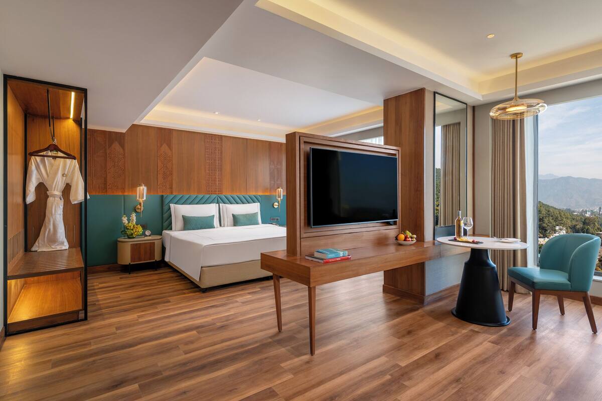 Una habitación de hotel moderna con cama, televisor, mesa de comedor y una silla.