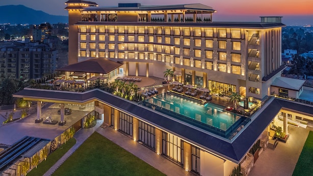 Un hotel moderno con una piscina grande, varios pisos y un exterior bien iluminado.