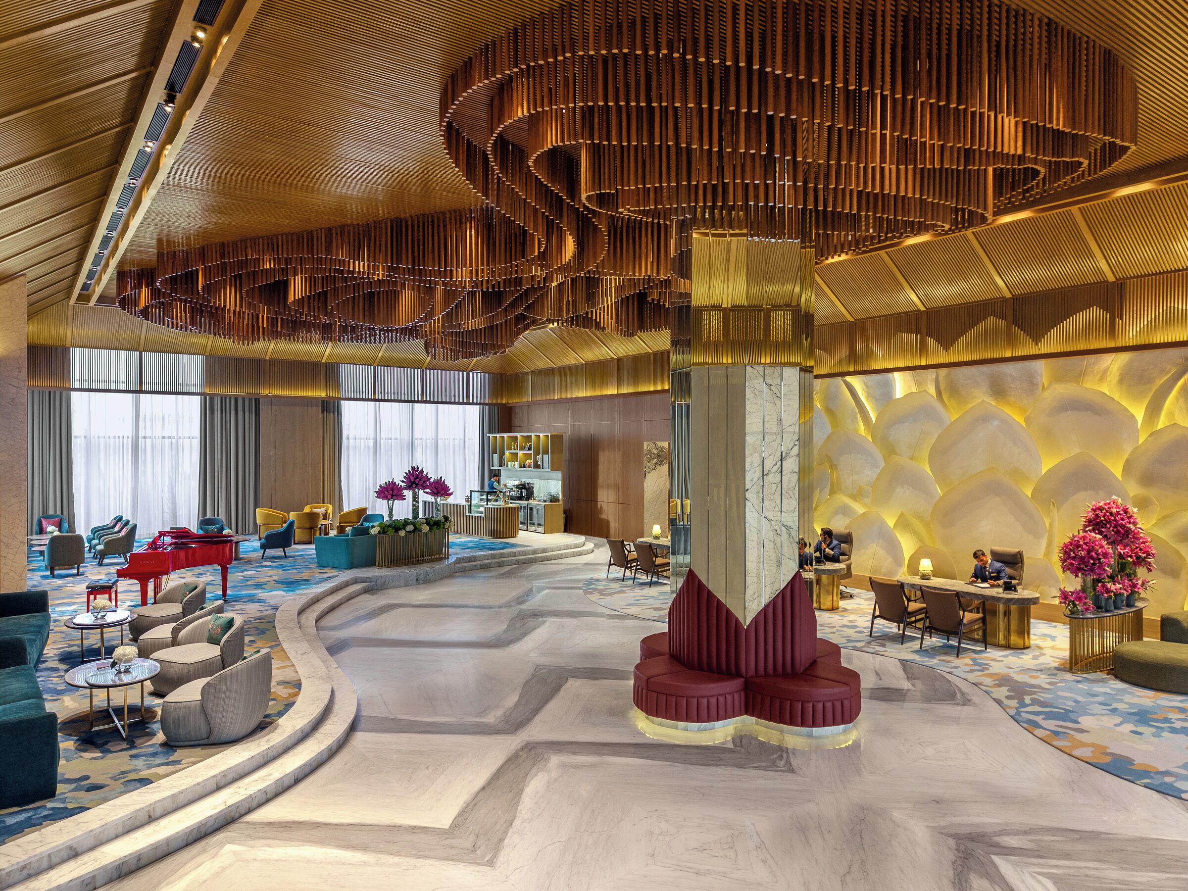 A spacious lobby with a central seating area, a reception desk, and a piano.