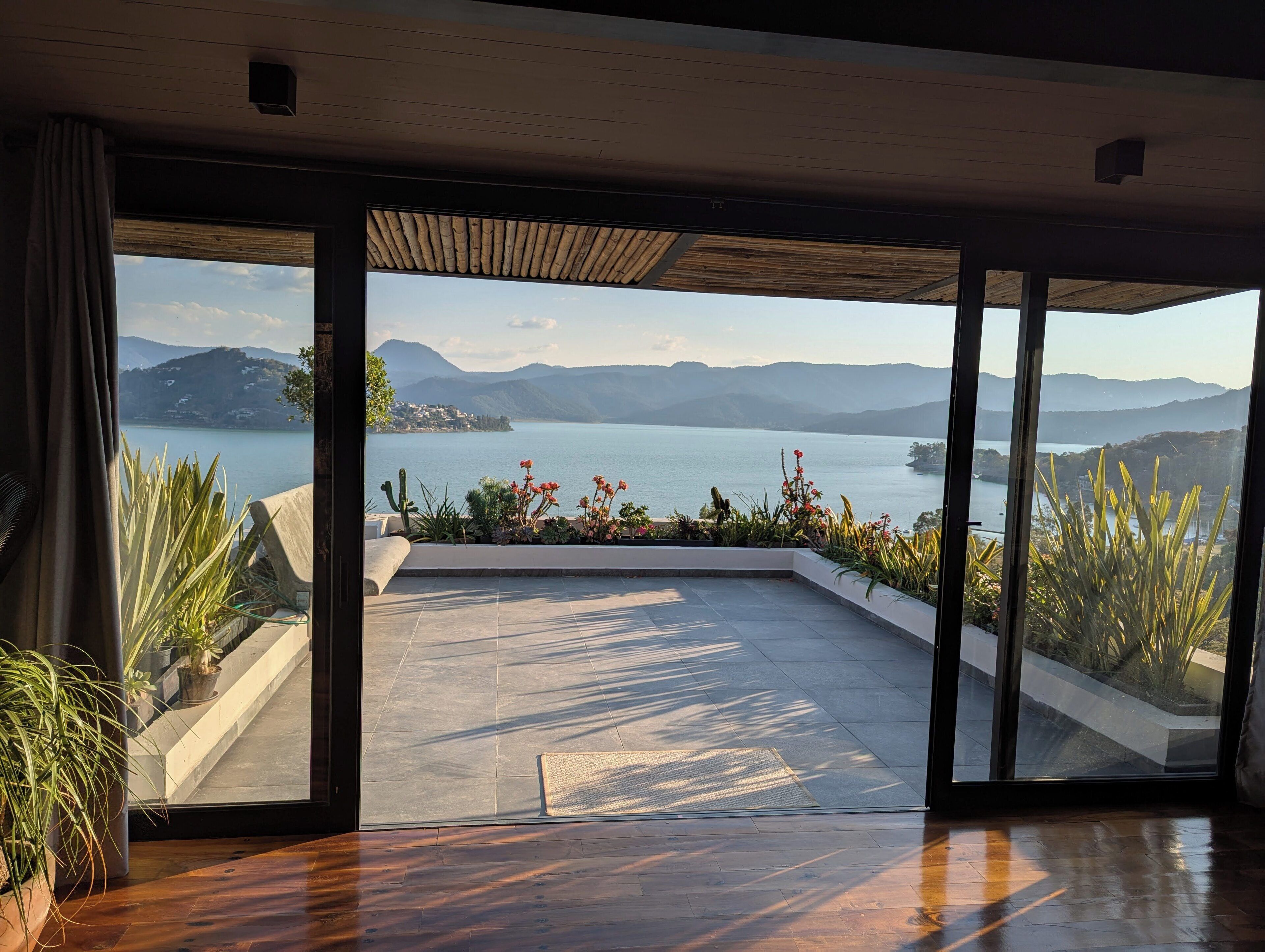 A spacious room with a large sliding glass door leading to a balcony overlooking a lake and mountains.