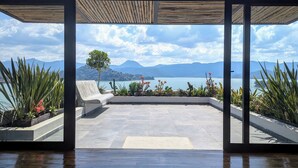 A spacious balcony with a view of a lake and mountains. - Designer House with Spectacular Lake Views, Jacuzzi and Lush Gardens (Valle de Bravo)