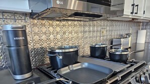 Una cocina con estufa de acero inoxidable, hervidor y ollas sobre la hornilla.