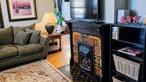 Una sala de estar con chimenea, sofá, televisor y estantería.