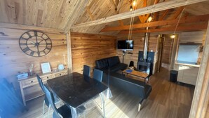 A cozy cabin interior with a wooden ceiling, a dining table with chairs, a sofa, a TV, and a fireplace. - Wooden chalet at the foot of the slopes 4-season ski resort CAMURAC (Camurac)