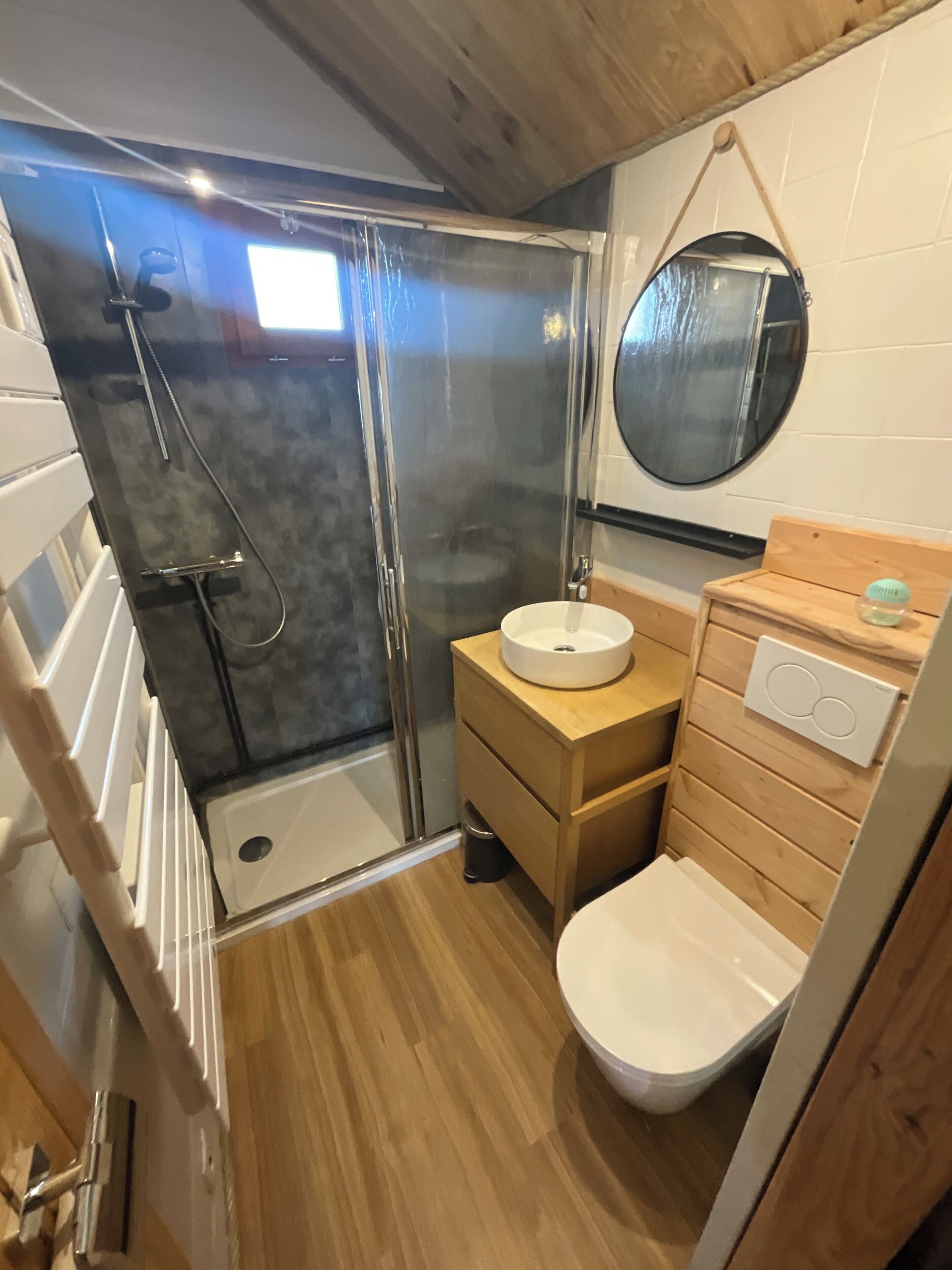 Une salle de bain compacte avec une douche à parois de verre, un meuble-lavabo en bois et des toilettes.