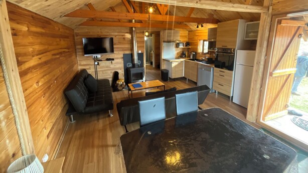 A cozy cabin interior with a living area, kitchen, and dining space. - Wooden chalet at the foot of the slopes 4-season ski resort CAMURAC (Camurac)