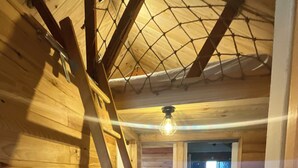 A wooden interior with a ladder, a ceiling light, and a doorway leading to another room. - Wooden chalet at the foot of the slopes 4-season ski resort CAMURAC (Camurac)