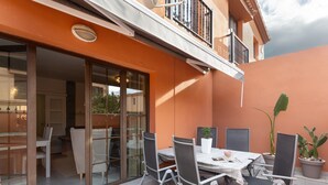 Un patio con una mesa y sillas, una planta en maceta y un cerramiento de vidrio corredera que da a un espacio interior.