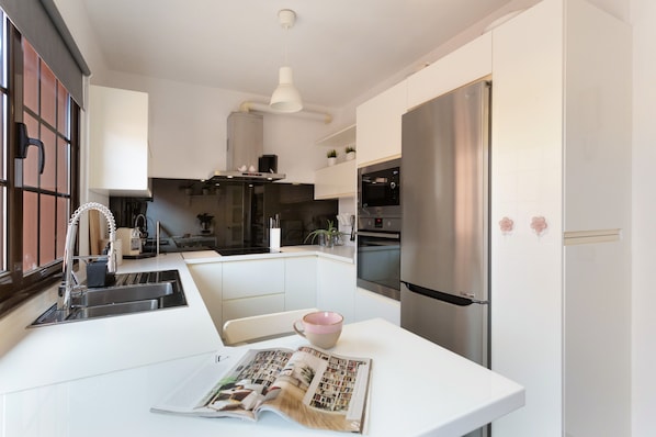 Una cocina moderna con una isla central, electrodomésticos de acero inoxidable y encimera blanca.
