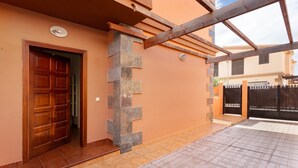Un edificio con puerta de madera, escalones de piedra y entrada con tejas.
