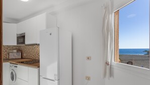 Una cucina con lavatrice, frigorifero e vista sulla spiaggia.