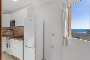 Eine Küche mit Waschmaschine, Kühlschrank und Blick auf den Strand.