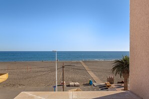 Blick auf einen Strand mit klarem Himmel, Sand und einer Palme.