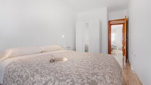 Una camera da letto con un letto, un armadio, un comodino e una porta che dà su un'altra stanza.