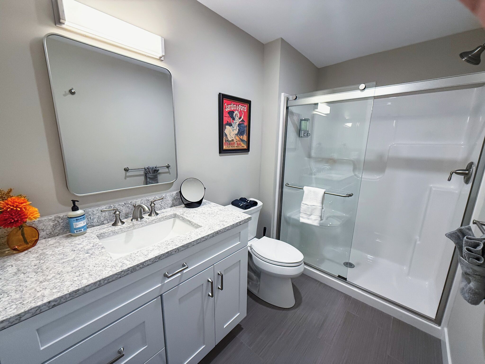 Une salle de bain moderne avec un lavabo en marbre, des toilettes et une douche à parois de verre.