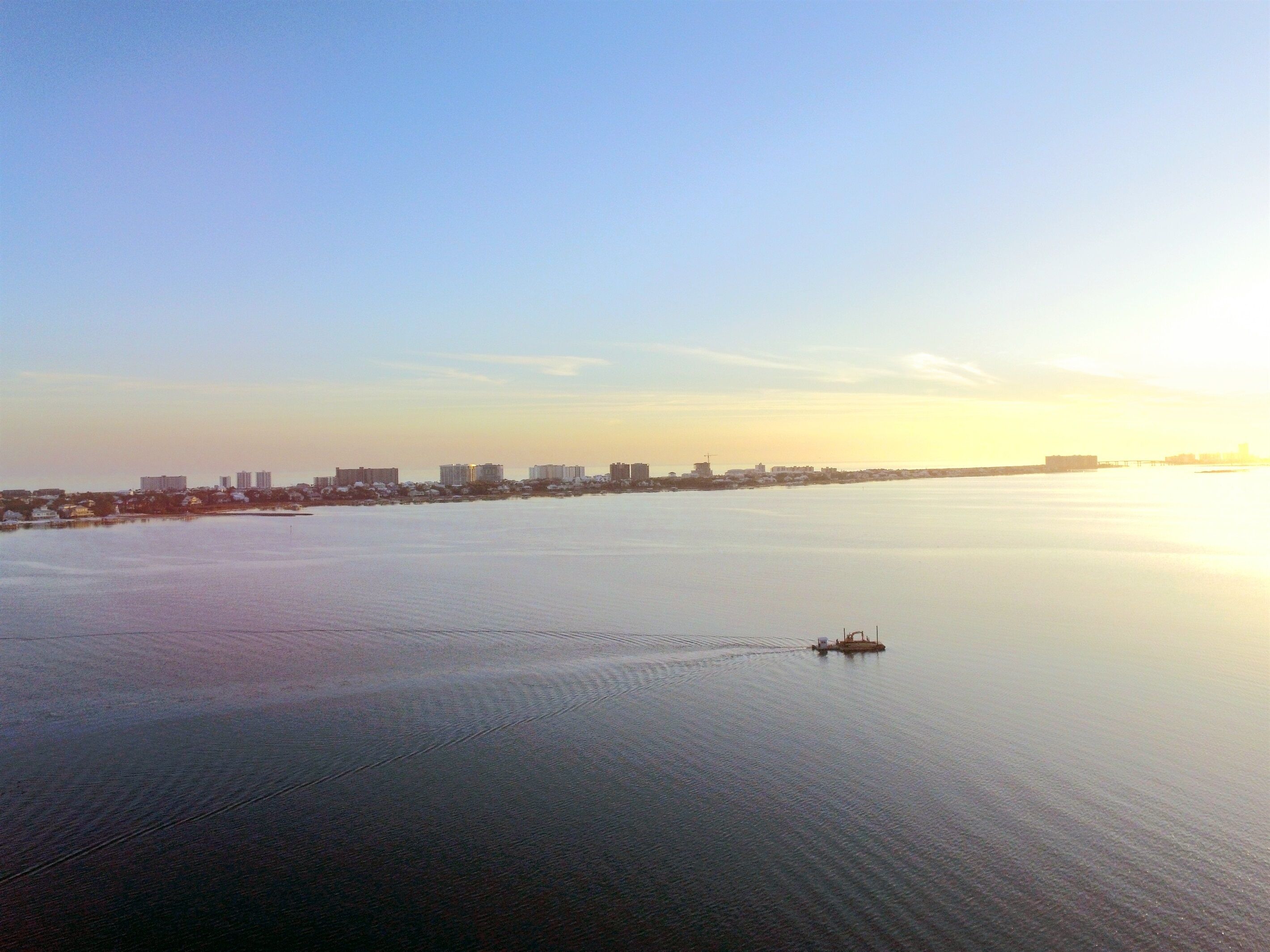 Una tranquila vista urbana de la costa con edificios a lo largo de la orilla y un pequeño bote en el agua.