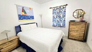 A bedroom with a bed, a dresser, a nightstand, a lamp, a painting, a curtain, and a mirror. - Bear Point Bay Front Beach House! Sleeps 12 (Orange Beach)