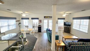 A spacious living area with a kitchen, dining table, and seating. - Bear Point Bay Front Beach House! Sleeps 12 (Orange Beach)